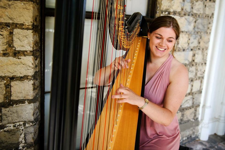 smiling harpist in pink dress at wedding drinks reception in buckinghamshire